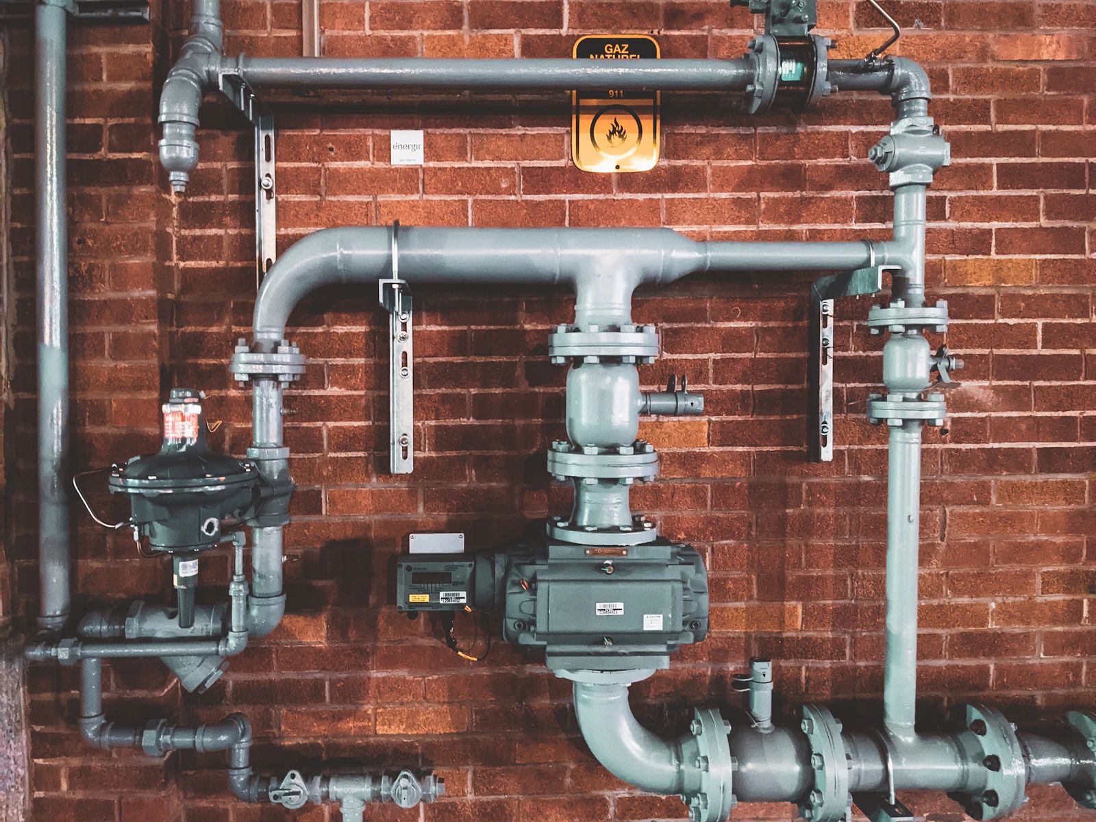 Industrial pipework mounted on a brick wall